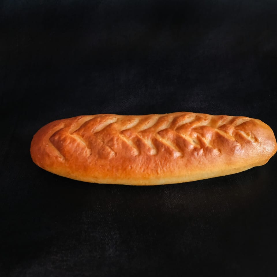 Golden-brown braided loaf of bread resting on a black background.