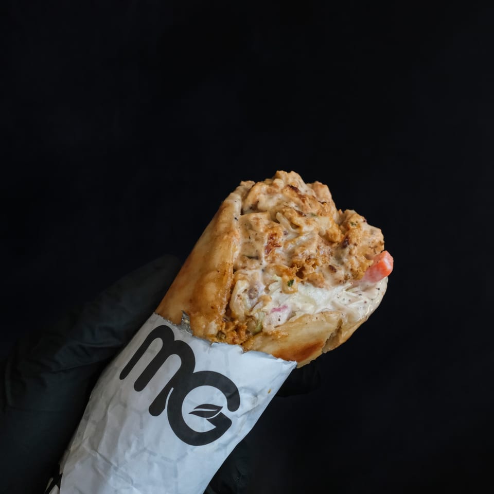 Filled sandwich held in an MG-branded paper wrapper.