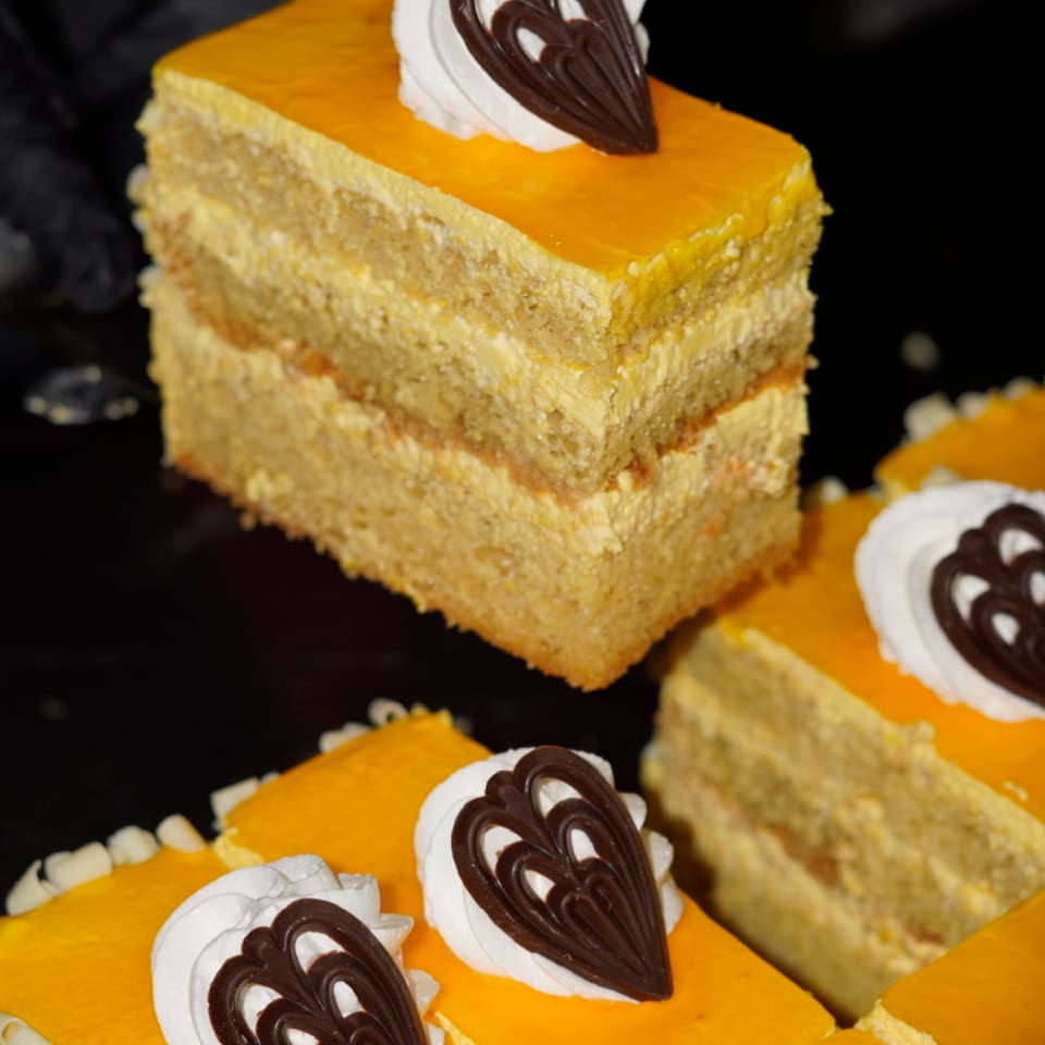 Yellow-glazed layer cake slices topped with cream and chocolate decorations.