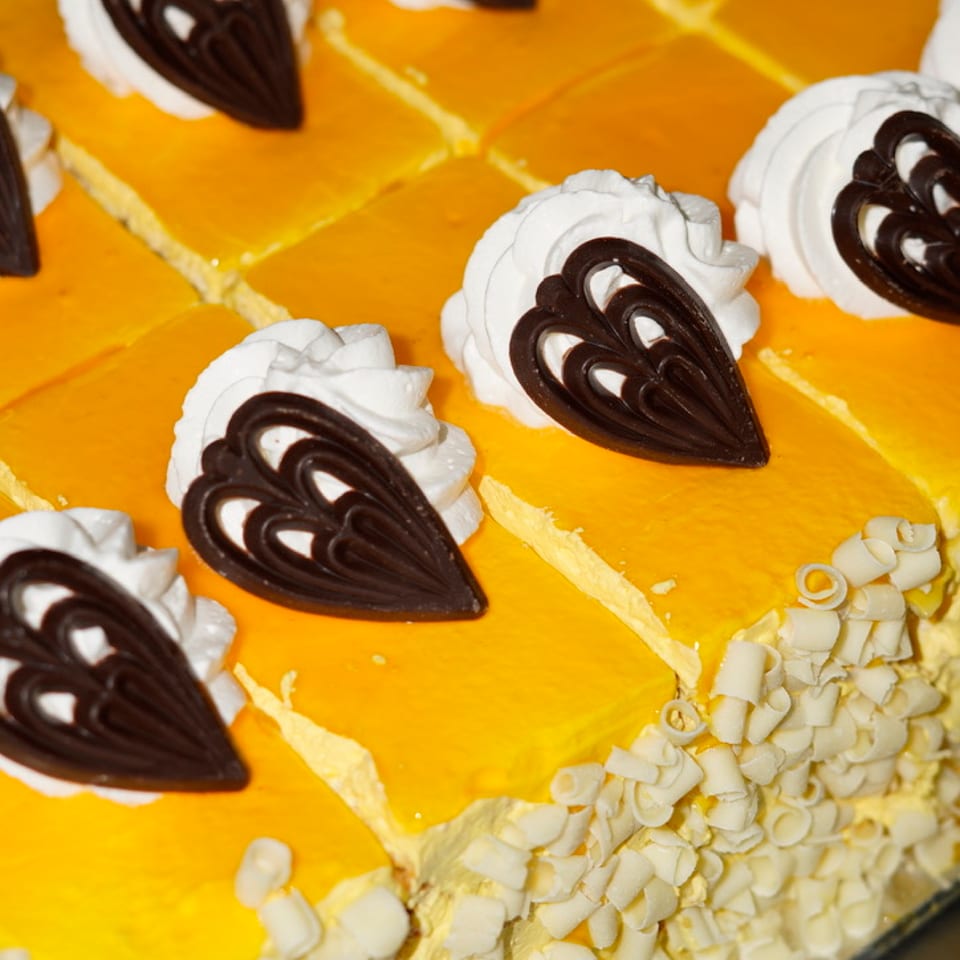 Yellow-glazed cake slices decorated with cream swirls and chocolate shapes.