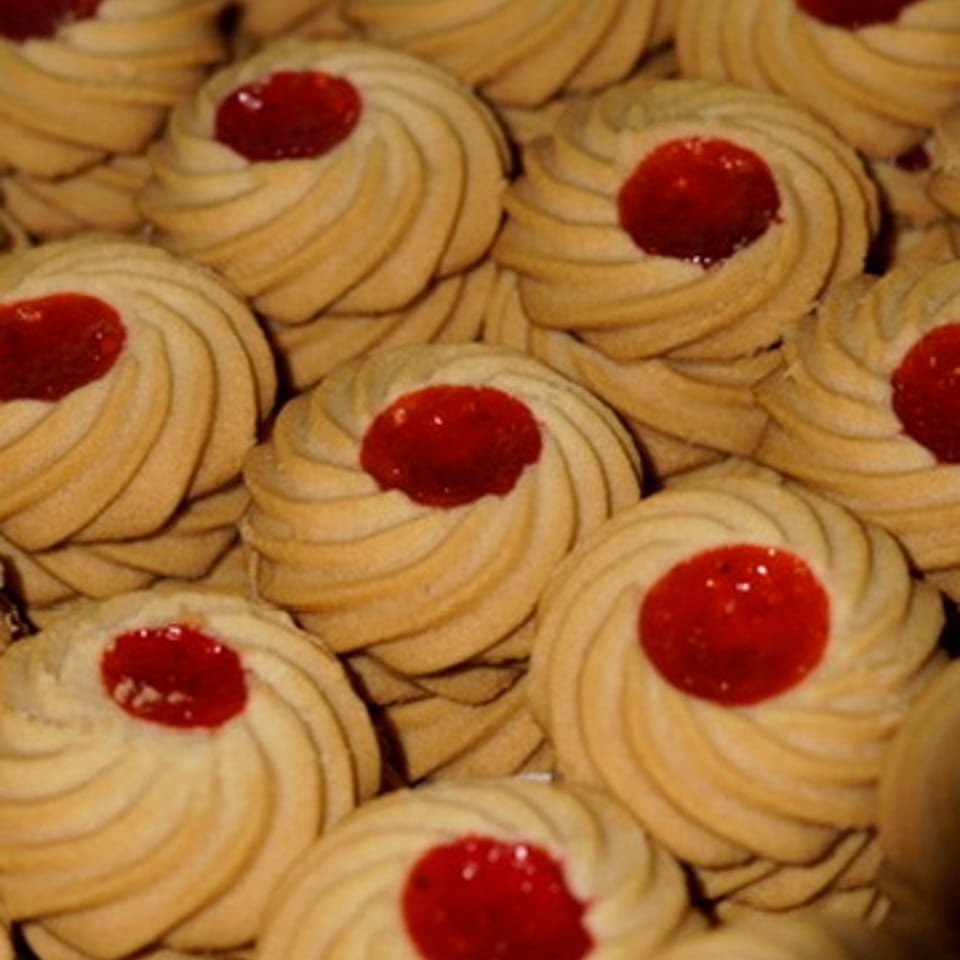 Golden piped cookies with glossy red centers.